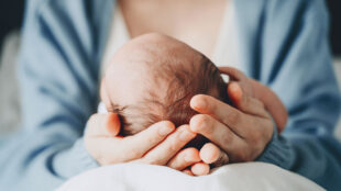 Mamma med nyfödd bebis i sitt knä.