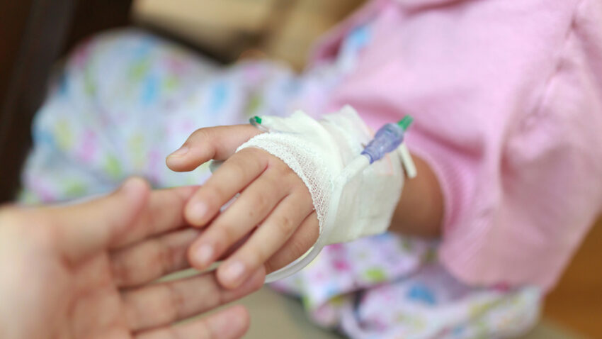 Sjukt barn håller mammas hand.