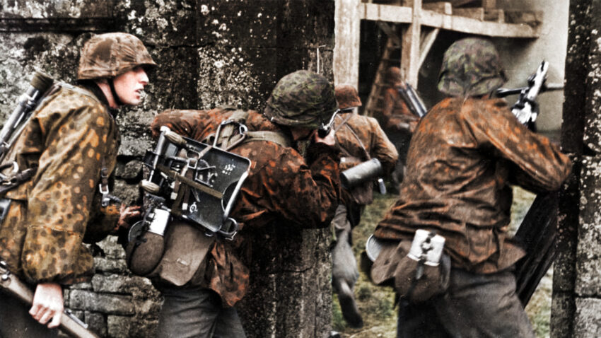 Soldater i Waffen-SS under andra världskriget, iförda kamouflagedräkter och beväpnade, i stridssituation nära stenmurar.