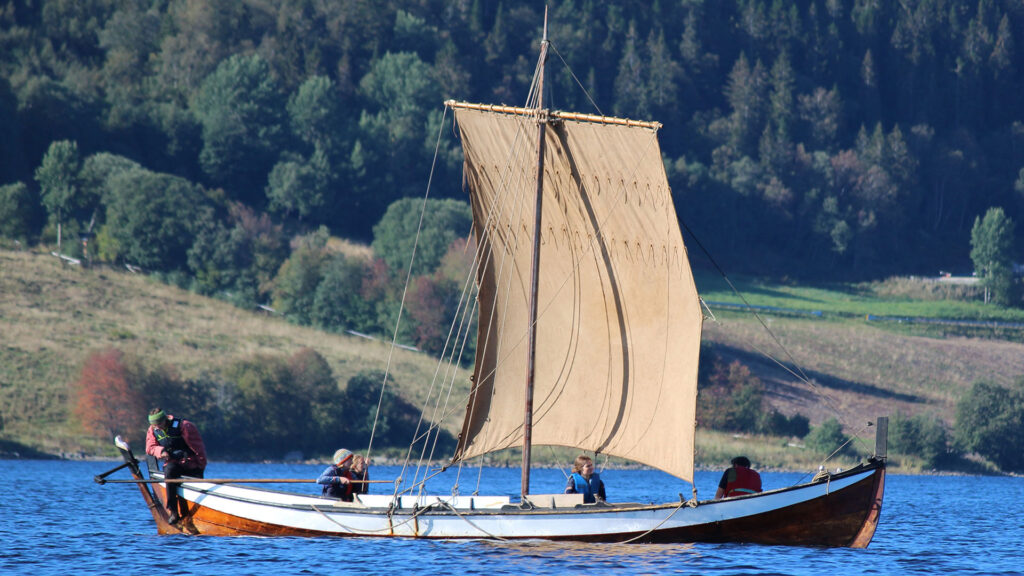 Rekonstruktion av ett vikingaskepp som seglar med fyra personer besättningen.