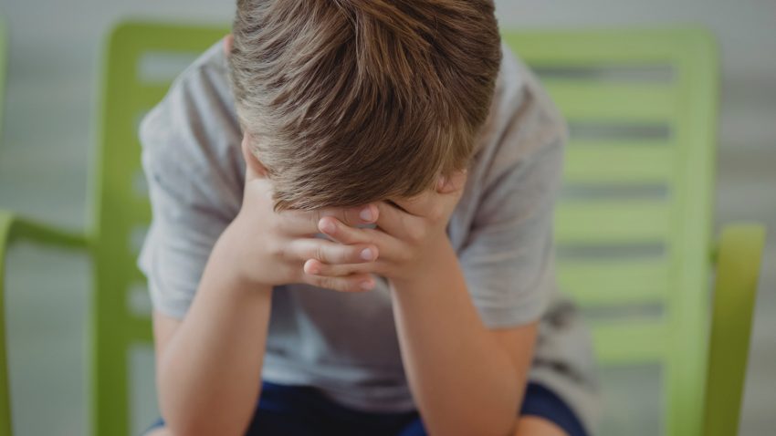 Pojke döljer sitt ansikte.